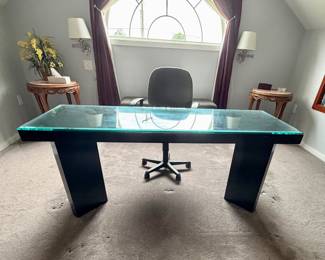 modern executive desk featuring a thick, tinted glass top and bold, angled black pedestal bases