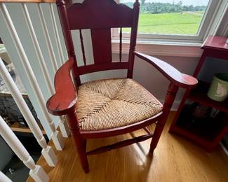 antique red-painted wooden armchair with a woven rush seat and spindle accents