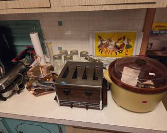 Kitchen counter with a vintage four-slot toaster, a yellow crock pot, a canister set, and assorted small kitchen items.