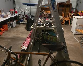 Aluminum step ladder and a vintage bicycle in the garage, with additional items in the background.