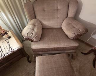 Taupe upholstered wingback armchair with button-tufted back, padded arms, wood trim, and skirted base, paired with its matching skirted ottoman. Clean, comfortable vintage seating.