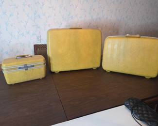 Same three-piece luggage set closed, shown from another angle with a quilted handbag nearby.