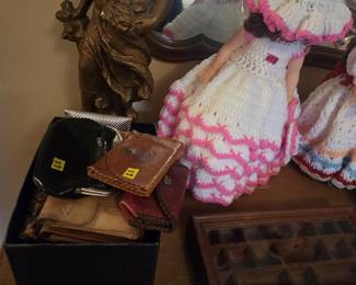 Bronze-finish spelter figurine of a woman in flowing classical dress, shown alongside a box of vintage coin purses and leather wallets, a glass-top wooden display case, and a handmade crochet-dressed bed doll with pink scalloped trim.