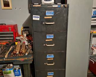 Tall gray metal filing cabinet in the garage, with a small radio on top.