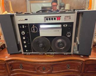 Vintage Sony reel-to-reel tape deck stereo system with built-in speakers, shown on a wood dresser.