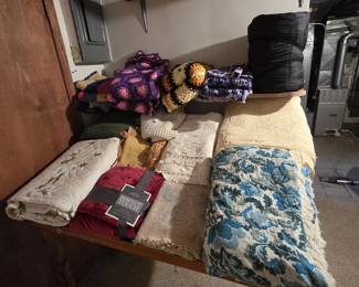 Large lot of vintage bedding and handmade textiles including granny-square and floral crocheted afghans, chenille and matelasse bedspreads in cream and yellow, a blue floral woven coverlet with fringe, a quilted floral comforter, and a new-in-package Perfect Touch throw blanket.