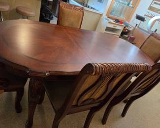 Close-up of the glossy mahogany-finish tabletop and ornately carved chair backs, highlighting the wood grain and finish.
