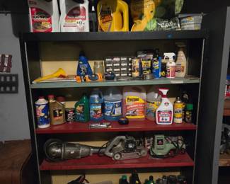 Metal garage shelving unit stocked with jars, motor oil, automotive fluids, and hand power tools.