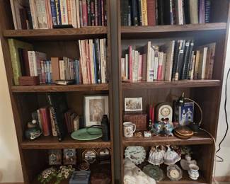 Pair of tall bookcases filled with fiction and reference books, Polish folk costume dolls, crocheted doilies, clocks, figurines, a framed Madonna and Child print, and boxes of hand-decorated Polish pysanky Easter eggs on the lower shelves.