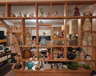 Large wood cubby-style display shelf densely filled with figurines, angels, dolls, and decorative collectibles.