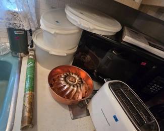 Counter lot with a green Stanley thermos, sealed Tupperware canisters with lids, a copper-tone fluted gelatin mold, a Hamilton Beach two-slice toaster in white, a roll of Kwik Kover shelf paper, and a Magic Chef microwave.