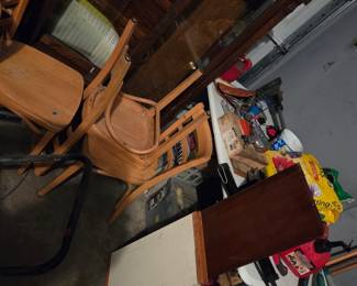 Garage storage area with stacked folding chairs, a small table, and assorted household items.
