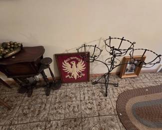 Polish heritage grouping featuring a framed felt applique banner reading Boze Zbaw Polske with a white eagle and crossed Polish and American flags, a wrought iron three-basket plant stand, an antique turned-leg side cabinet, and a wooden pedestal plant stand.