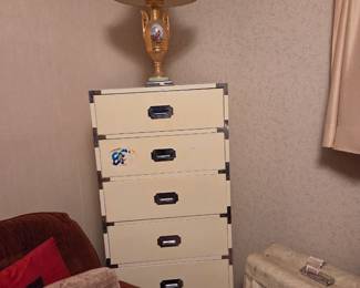 Five-drawer white stacking storage unit, topped with a gold ornate table lamp.