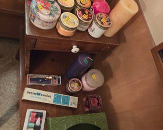 Shelf holding an assortment of candles and craft supplies.