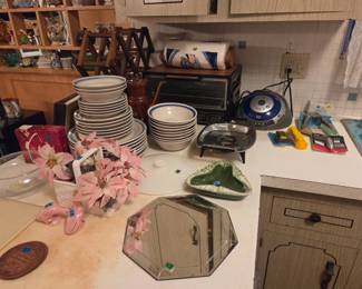 Kitchen counter with stacks of white dinnerware plates and bowls, a small mirrored tray, and a kitchen scale.