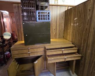 Mid-century modern blonde credenza with four drawers over double cabinet doors and a slotted interior rack, shown with a stack of vintage milk crates including a Borden dairy crate, and two olive-green metal storage boxes.