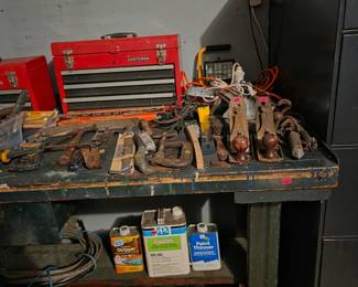 Workbench with a red toolbox, bench vises, and hand tools, next to a metal storage cabinet.