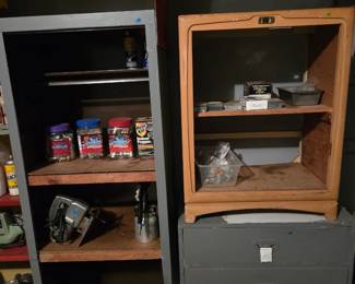 Garage shelving with cans of paint or stain, a small wood stand, and a gray metal three-drawer filing cabinet.