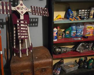 Garage shelving with automotive fluids and supplies, above two vintage wood storage drawers.