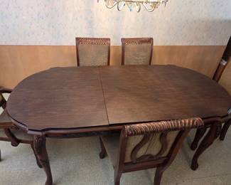 Oval table with the extension leaf visible down the center, alongside matching cane-back chairs from the first dining set.
