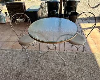 Round patio table with glass top and two ice cream parlor style chairs measures 31 inches across