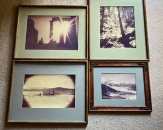 dy- Lot of four framed vintage photographs featuring a variety of scenic and travel subjects. Images include a dramatic sunburst through ancient classical ruins, a wooded forest scene, a snow-covered church or monastery in a mountainous landscape, and a panoramic snow-covered mountain valley. All four are presented under glass with matting in assorted wood-tone frames. The photographs appear to have some age. No photographer signatures, titles, dates, or definite locations are visible in the photos provided. Green Vertical Frame: 21in x 16.5in Green Horizontal Frame: 16.7in x 20.7in Larger Blue Wood Frame: 16.7in x 20.7in Smaller Blue Wood Frame: 13.5in x 16.5in