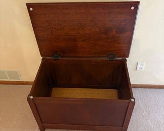cv- This wooden toy chest is designed for the main bedroom, crafted from high-quality wood with a rich mahogany finish. It features a spacious interior with dimensions of 21 inches tall, 34 inches wide, and 21 inches deep, providing ample storage for toys or other items. The chest includes a sturdy hinged lid with metal supports for safe and easy opening. Its durable construction and classic design make it both functional and stylish for any bedroom decor.