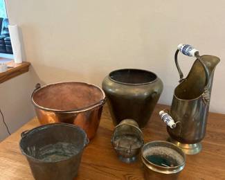 fy- A diverse set of assorted metal canisters featuring a variety of shapes, sizes, and materials including brass, copper, and tin. Highlights include a tall brass canister with elegant white and blue ceramic handles, a hammered copper bowl with a rustic patina, and an antique brass pitcher with intricate lion head detailing on the handle. Each piece showcases unique metal finishes and aged character, ideal for collectors or decorative use.