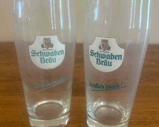 kh- This set features two Schwaben Bräu branded pint glasses, distinguished by their clear glass material and iconic logo printed on the front. Each glass stands approximately 6.75 inches tall with a diameter of about 3 inches at the top, making them ideal for serving a full pint. The slender, cylindrical design offers an elegant presentation while highlighting the detailed Schwaben Bräu emblem in green and brown hues. Perfect for collectors or beer enthusiasts seeking authentic brewery glassware.