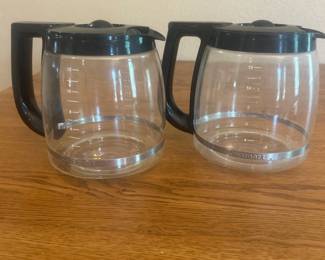 ju- This set includes two authentic Cuisinart coffee pots, perfect for brewing and serving your favorite coffee. Each coffee pot is made of clear glass, allowing you to easily monitor the coffee level. They feature sturdy black plastic lids with a central knob and black ergonomic handles for comfortable pouring. Measuring approximately 6 inches tall, these coffee pots are ideal replacements or extras for your coffee maker. Their classic design blends seamlessly with any kitchen decor while providing reliable functionality.