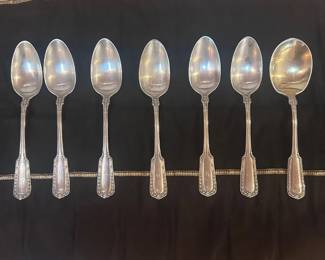 ao- Group of 7 antique Gorham sterling silver spoons, including 6 smaller spoons and 1 larger soup spoon. Each features an ornate paneled handle with decorative border detailing. Pieces are marked STERLING with Gorham hallmarks and additionally stamped “GUS. J. KRAY,” a period retailer mark. Several handles appear monogrammed. Includes the brown storage roll shown. Surface scratches, patina and tarnish consistent with age and use. Total weight 6.3 oz