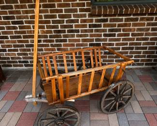 ag- Charming antique wooden farm or utility wagon, believed to date to the early 20th century, approximately 1900–1930. Features a slatted wooden box body, plank floor, long wooden pull handle, and four traditional wooden spoked wheels with metal rims and hardware. The wagon displays the craftsmanship and utilitarian construction associated with early farm and homestead equipment. It shows considerable age and character throughout, including weathering, finish wear, surface marks, oxidation, and other signs of longtime use. Some hardware and fasteners appear to be later replacements or repairs, and the pull handle may also have been replaced at some point. Approximate dimensions: 44” L x 34” W x 25” H, excluding extended pull handle. Condition: Antique condition with expected wear from age and use. Please review all photographs closely for construction, condition, and completeness.