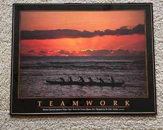 ei- This motivational poster titled 'TEAMWORK' showcases a striking silhouette of six individuals paddling a canoe against a vivid orange and pink sunset over calm waters. The black and gold bordered frame complements the warm hues of the sky, creating a visually inspiring piece. Made with glossy paper and mounted on a sturdy backing. It includes an inspiring quote emphasizing collaboration and collective effort, making it ideal for office or team environments.