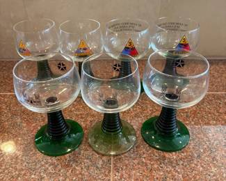ln- This set of 7 Luminarc Roemer style wine goblets features a distinctive green beetive or ribbed stem, adding a unique touch to each glass. These military collectible goblets stand 5.5 inches tall with a 3-inch diameter, making them perfect for display or special occasions. Each goblet is adorned with military insignias and markings, including colorful division emblems and detailed inscriptions, celebrating military heritage in an elegant and functional design.