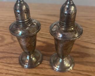 ap- Vintage pair of pedestal-form sterling silver salt and pepper shakers with removable perforated tops. Each features a tapered body, flared shoulder and round weighted foot. Undersides are marked “STERLING” and “WEIGHTED” surrounding a decorative maker’s emblem. Both pieces show natural tarnish, surface scratches and age-related wear, particularly around the shoulders and shaker tops. No polishing has been attempted. Attractive classic form suitable for use, display, or a sterling silver collection.