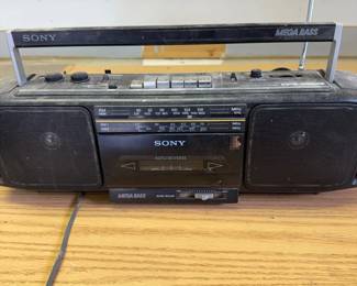 mp- This vintage Sony CFD-S12OS boombox radio features a classic black design with a sturdy plastic casing. It includes dual built-in speakers and a Mega Bass feature enhancing audio quality. The device supports cassette tape playback and radio tuning with an extendable metal antenna for improved reception. Compact and portable, it is designed with a carrying handle and simple control buttons on top for easy operation. Ideal for collectors or those seeking retro audio equipment with authentic sound and nostalgic value.