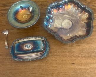 fq- This set includes four assorted silver-plated pieces featuring a beautiful iridescent finish with hints of blue and gold tones. The collection showcases various shapes including a scalloped bowl approximately 10 inches in diameter, a footed pedestal dish, a butter dish and a small spoon. Each piece exhibits unique patination and reflective qualities typical of vintage silver plating. The material offers a charming antique appeal, perfect for collectors or decorative display.