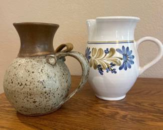 av- This charming decorative pitchers features a rustic, handmade design with a distinctive speckled glaze that blends earthy beige and brown tones. Measuring approximately 7 inches tall and 6.5 inches wide, it boasts a rounded body and a flared spout for an elegant yet functional silhouette. The handle has a unique looped accent that adds to its artisanal appeal. Crafted from ceramic, these pitchers are perfect as a decorative piece or for serving beverages, showcasing a beautiful textured finish and a warm, neutral color palette that complements various home styles.