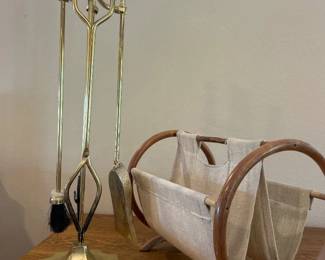 fx- This elegant fireplace essentials set includes a polished brass tool set featuring a shovel, brush, poker, and tongs with decorative handles, perfectly designed to maintain your hearth. Accompanied by a sturdy wooden frame log holder with natural-finish curved handles and a durable beige fabric sling, this set combines functionality with timeless style. The brass tools offer a gleaming golden tone that contrasts beautifully with the warm wood and neutral fabric, making it a practical and attractive addition to any living space.