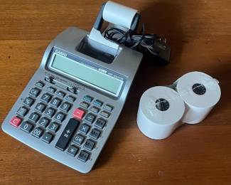 ls- This Casio HR-100TE printing calculator features a large LCD display and a built-in thermal printer for fast, easy calculations with printed records. Highlighted by its gray plastic body, this model offers a wide numeric keypad with specialized function keys, including cost, sell, margin, and tax calculations. The device includes a power adapter for reliable use and two rolls of 2 1/4 inch by 130 foot thermal paper, ensuring extended operation without frequent replacements. Its compact and robust design makes it ideal for office or retail environments requiring quick, precise, and documented arithmetic.