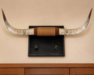 be- Impressive set of genuine longhorn cattle horns mounted on a substantial rustic wood wall plaque. The horns have a natural cream, gray and brown coloration with darker tips and are wrapped at the center with decorative rope and braided material. The dark-stained wood plaque adds a strong Western/ranch-style presentation. Measures approximately 60” from horn tip to horn tip and projects approximately 20” from the wall. Wood mounting plaque measures approximately 26.5” W x 17.5” H. The horn tips show some chips, surface wear and small areas of loss, as pictured. Additional natural surface variations and wear are present throughout. Please review all photos for condition.
