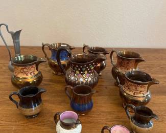 az- A charming collection of assorted decorative hand-painted miniature pitchers featuring intricate designs and a variety of colors. This set includes small pitchers measuring approximately 2.5 to 3.5 inches in height, with distinctive textured white exteriors and glossy pink interiors, accented by dark brown rims and handles. Perfect for collectors or as decorative accents, these finely crafted ceramic pieces showcase both elegance and artistic detail.