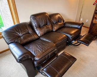 gu- This La-Z-Boy reclining couch features rich dark brown leather upholstery, offering both comfort and style. Designed to seat three, it includes two reclining seats with footrests for ultimate relaxation. The couch measures 40 inches tall, 87 inches wide, and 36 inches deep when unreclined. Crafted for durability and comfort, this classic leather couch is perfect for enhancing any living room setting.