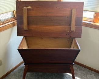 at- This antique wooden dough box features a large, deep interior perfect for storage or display. Historically used in 19th-century farmhouses for mixing and letting bread dough rise. Crafted from rich, warm wood, it stands 28 inches tall with a 40 inch wide top and a 21.5 inch deep top. The box rests on elegantly turned legs, showcasing traditional craftsmanship. Its sturdy hinged lid opens to reveal a spacious compartment, ideal for keeping items secure and organized. The natural wood finish highlights the vintage character and timeless appeal of this unique storage piece.
