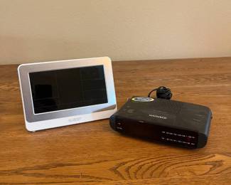 mh- This set includes a compact black MAGNAVOX clock radio with AM/FM functionality and an attached power cord, complemented by a separate white digital La Crosse display screen. The display screen boasts a modern rectangular shape with a black screen and white frame, perfect for clear visibility on your bedside or desk. The clock radio unit features intuitive buttons for alarm, time, and radio controls, with a red LED display for easy time reading even in low light.