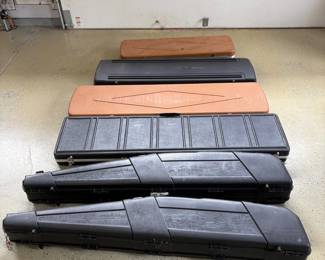 hsThis collection features an assortment of rifle cases designed to accommodate rifles of various sizes. The cases come in two primary colors: black and tan, with sturdy construction evident in the durable plastic and wood-like materials. The larger black cases have a rugged, molded design with secure latches, ideal for protecting firearms during transport. The tan and dark gray cases appear to be made from hard composite materials, offering additional options depending on size and style preferences. Perfect for shooters or collectors needing reliable rifle storage solutions. Cases do not have keys.