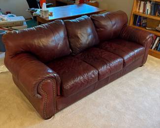 gw- This brown leather couch features a rich, warm tone and a durable leather material that offers both comfort and style. Measuring 34 inches tall, 90 inches wide, and 36 inches deep, it provides ample seating space for a living room or office. The couch is designed with plush, overstuffed cushions for superior comfort and classic nailhead trim accents that add a touch of elegance. Constructed with polyurethane foam and polyester fiber filling, it ensures long-lasting support and durability. Made in Mexico, this piece combines functional design with traditional aesthetics, making it a versatile addition to any seating area.