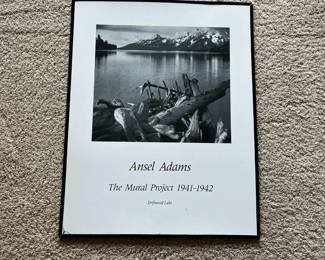 ek- This framed black and white photographic print features Ansel Adams' iconic image from The Mural Project 1941-1942, titled 'Driftwood Lake.' The piece highlights Adams' masterful landscape photography capturing serene natural scenery with driftwood in the foreground and snow-capped mountains in the background. Presented within a sleek black frame, the print measures approximately standard poster size. The versatile monochrome tones complement a variety of decor styles, making it a timeless addition for photography enthusiasts and art collectors.