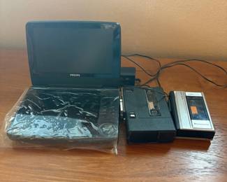 cr- This lot includes a Philips PET941A/37 portable MP3 and DVD video player, featuring compact design and playback support for DVDs, MP3 CDs, and DivX videos. The player is black and comes with a built-in control panel. Alongside it, there is a GE cassette player and recorder for analog tape media, as well as a Panasonic Mini Cassette Recorder model RQ-310, ideal for recording and playback on mini cassettes. All devices are vintage electronic media players, perfect for collectors or those interested in legacy audio-video equipment.